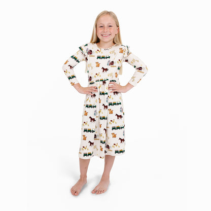 Child in On the Farm bamboo ruffled long sleeve twirl dress with horse and tractor print, soft and breathable for sensitive skin.