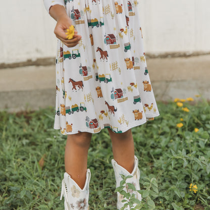 On the Farm bamboo ruffled twirl dress fabric close-up showing tractor and horse print, breathable and hypoallergenic bamboo fabric.