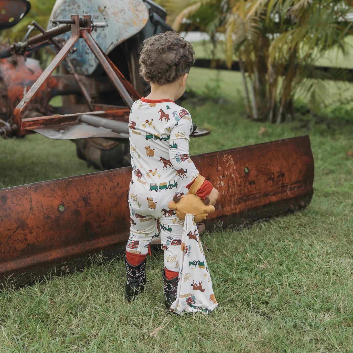 Child holding On the Farm bamboo security blanket lovey with farm print, soft, breathable comfort for kids.