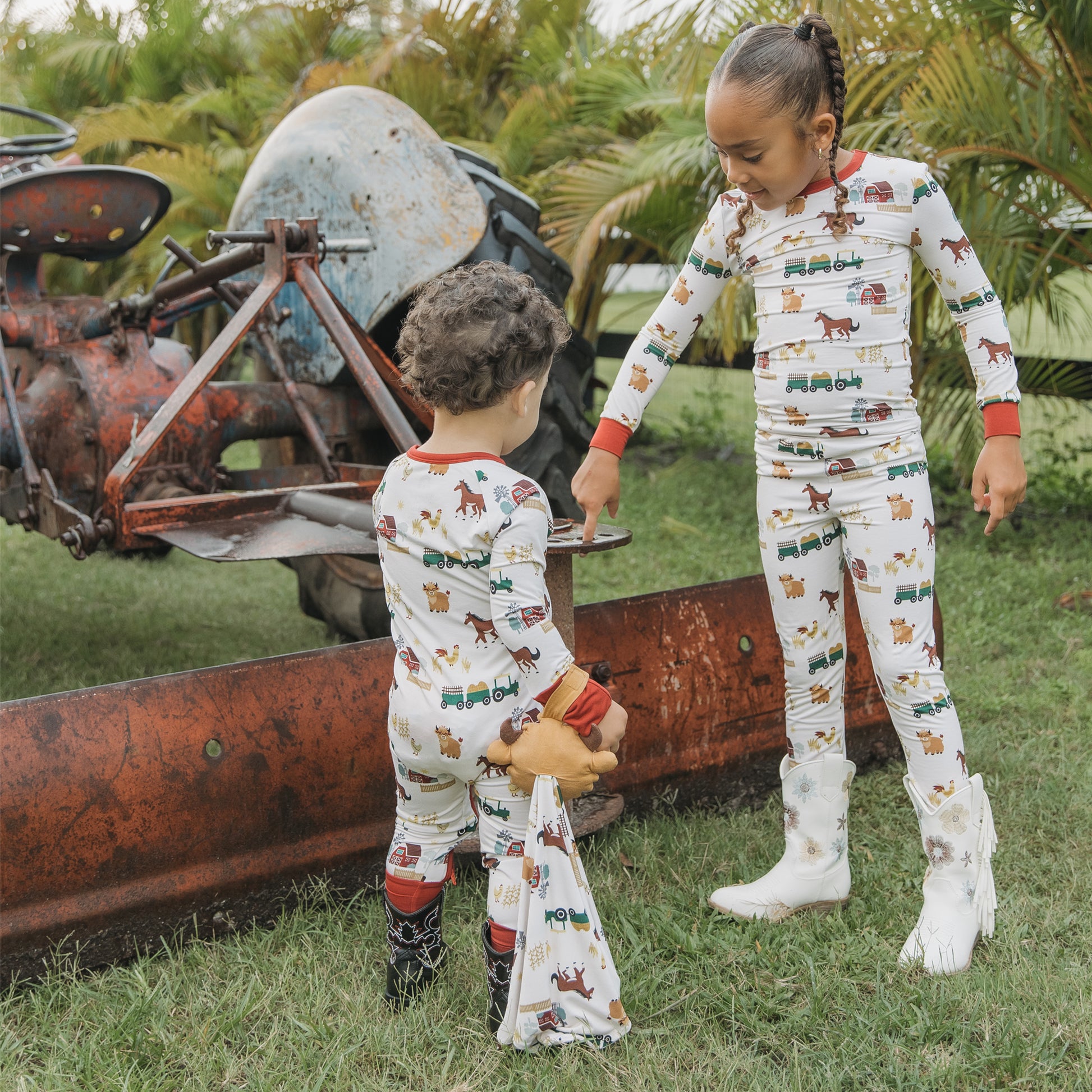 Two siblings in matching On the Farm bamboo pajamas holding security blanket lovey, breathable and hypoallergenic for sensitive skin.