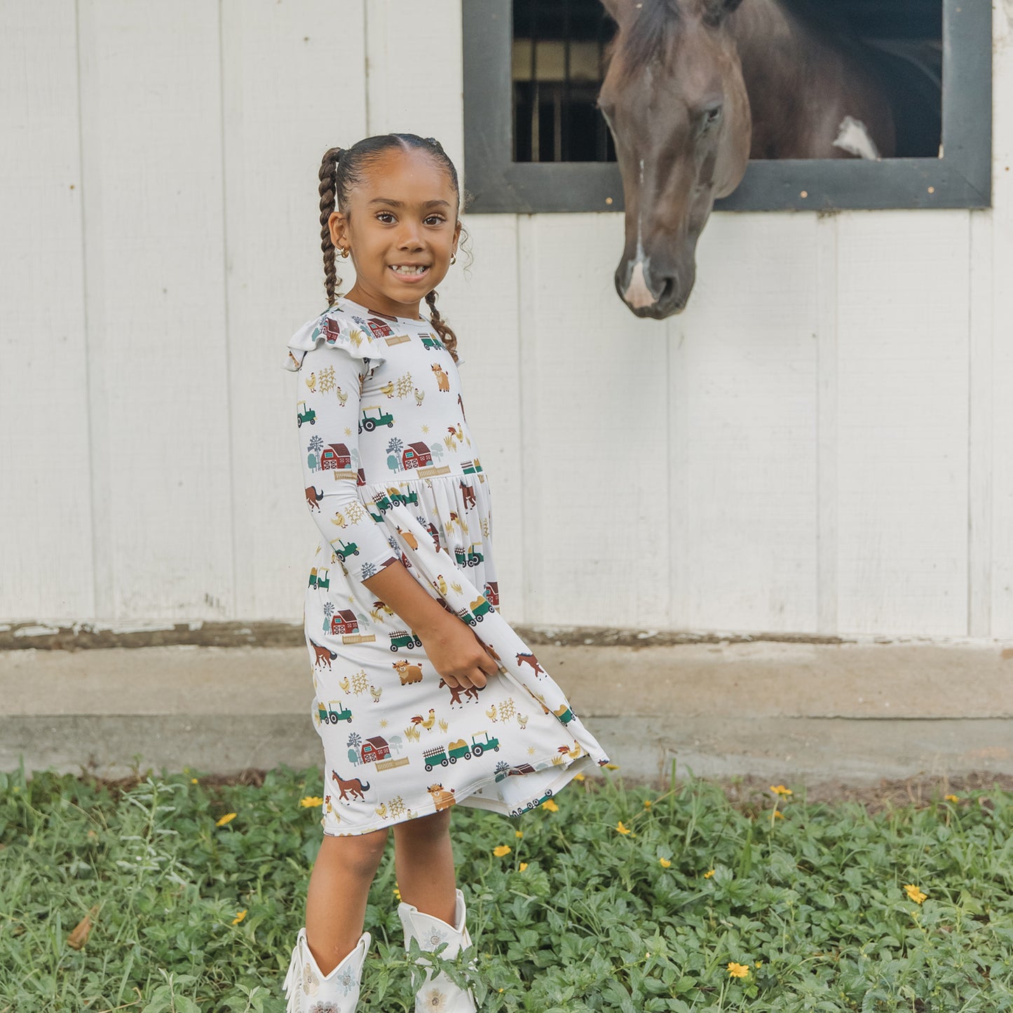 Child wearing On the Farm bamboo ruffled twirl dress with farm print of horses, cows, and tractors, soft and breathable fabric