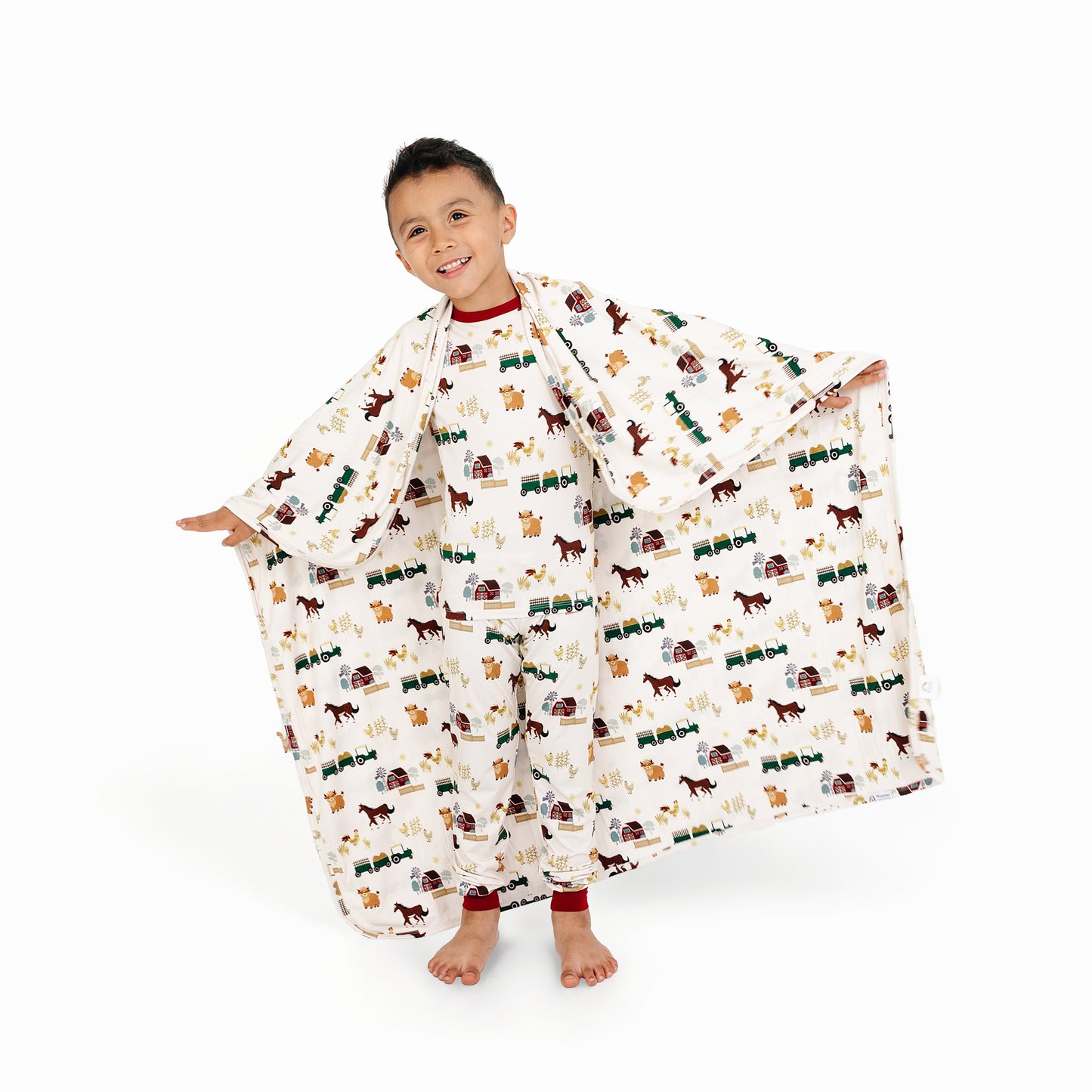 Child holding out On the Farm luxury bamboo blanket showing horse and cow farm print, breathable and soft fabric for sensitive skin.