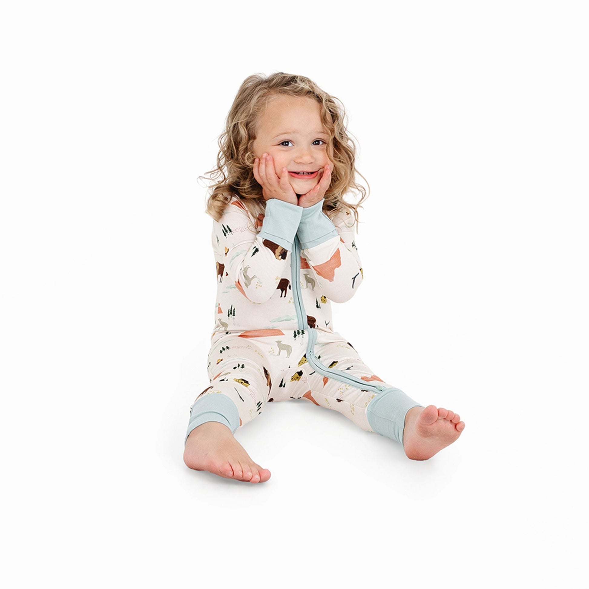 Child wearing a patterned onesie with light blue accents on a white background