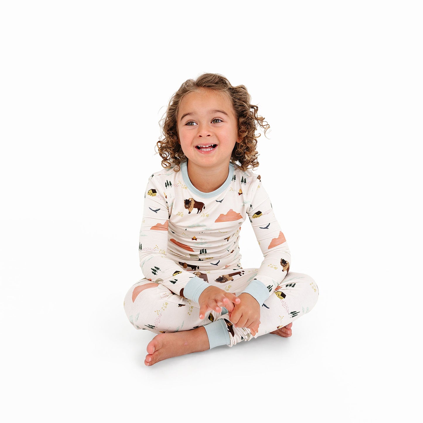 Child wearing a patterned onesie sitting on a white background