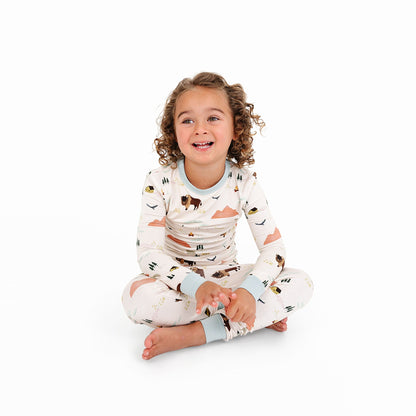Child wearing a patterned onesie sitting on a white background