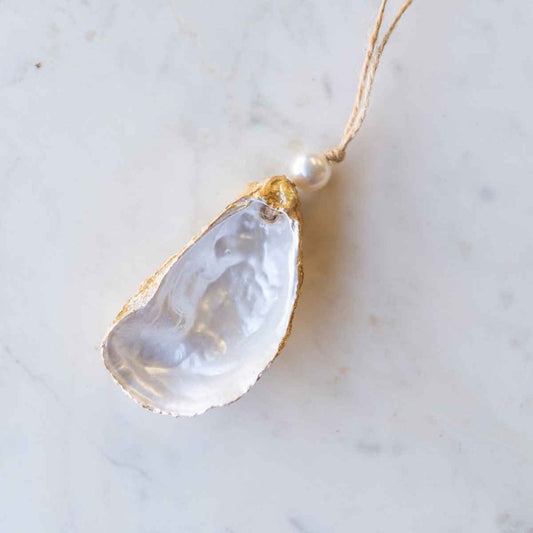 painted oyster shell ornament with a pearl bead on top