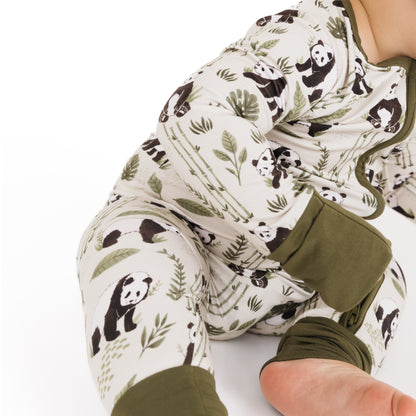 Baby in a onesie with panda and leaf pattern on a white background
