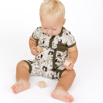 Baby wearing a romper with panda print, sitting on a white background