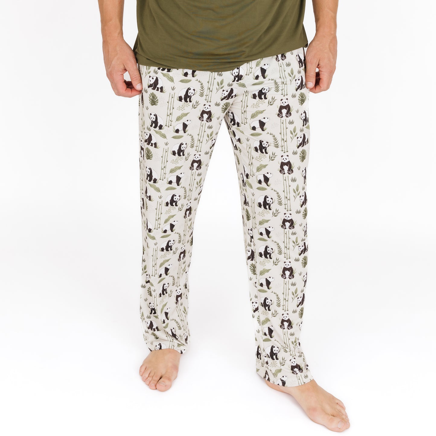 Person wearing pajama pants with panda and leaf pattern on a white background
