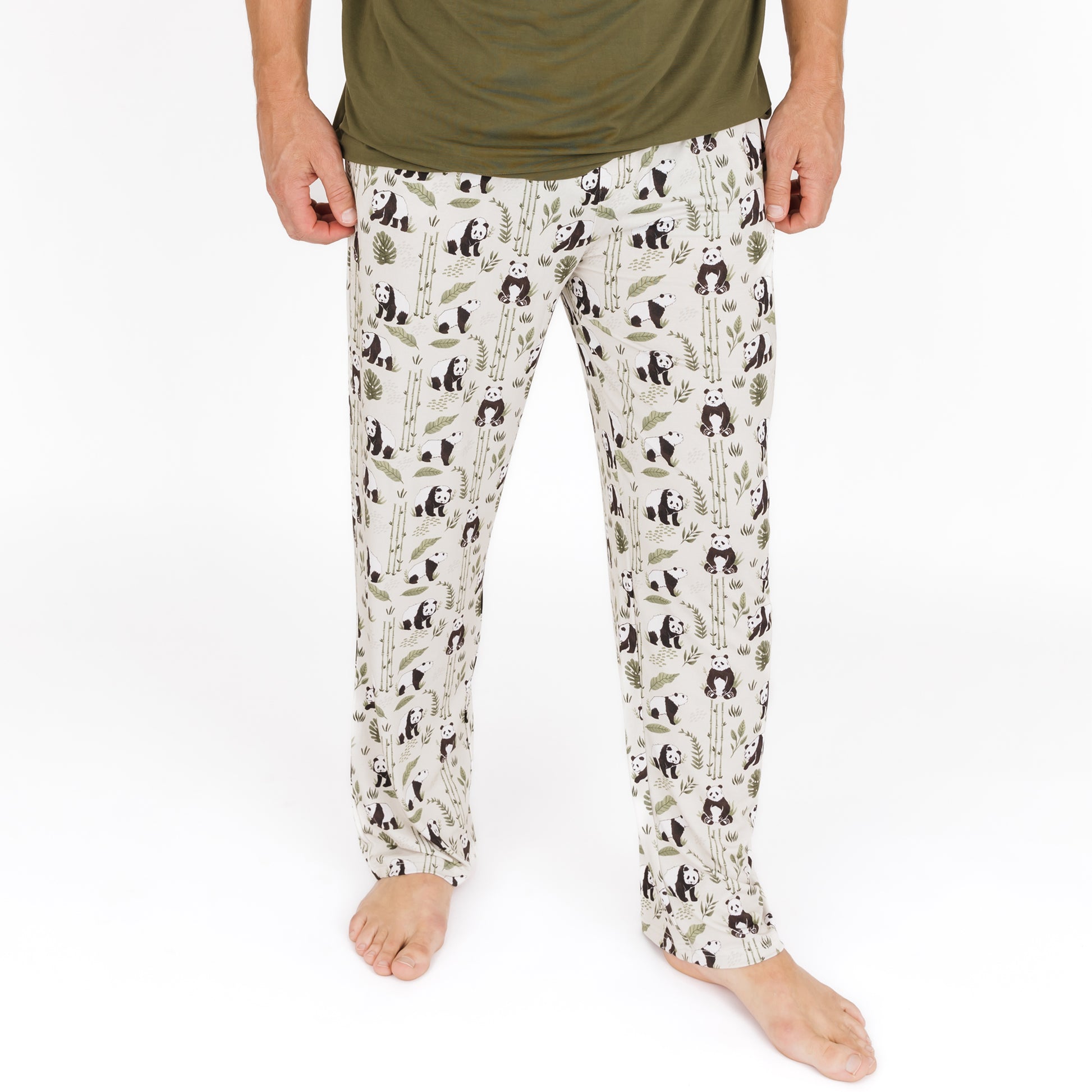 Person wearing pajama pants with panda and leaf pattern on a white background