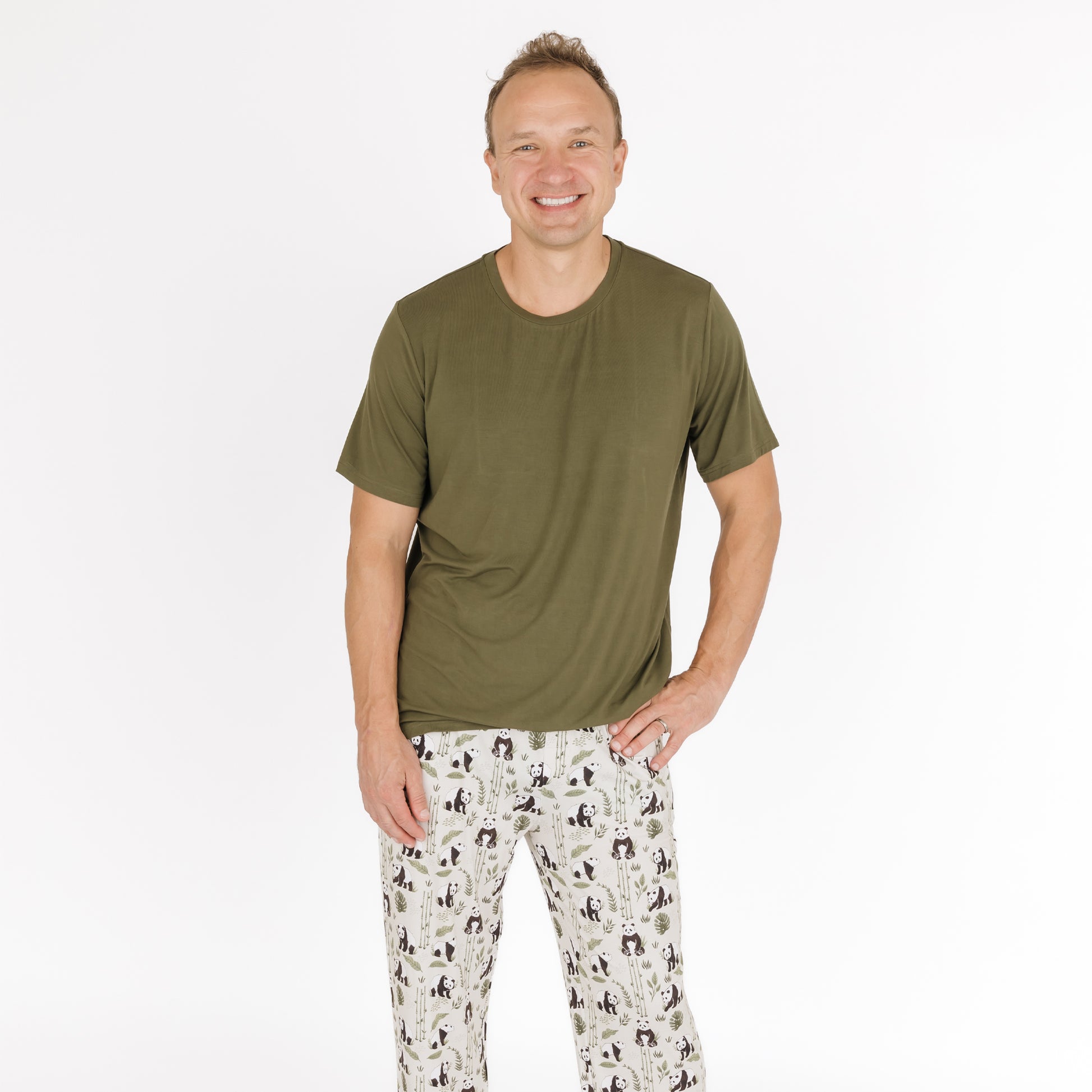 Man wearing an olive green t-shirt and patterned pants on a white background