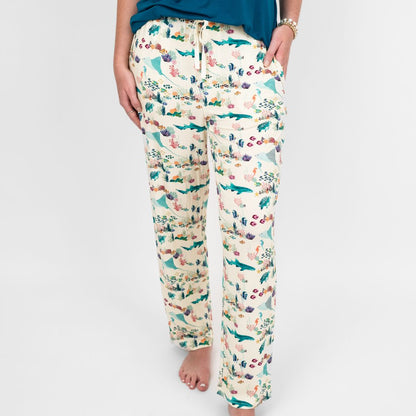 Woman smiling and wearing our Emerson and Friends Coral Reef Bamboo Relaxed Lounge Pajama Pants, featuring a serene ocean-inspired print with sea turtles, sharks, coral, and tropical fish on ultra-soft bamboo fabric perfect for all-day comfort and night.