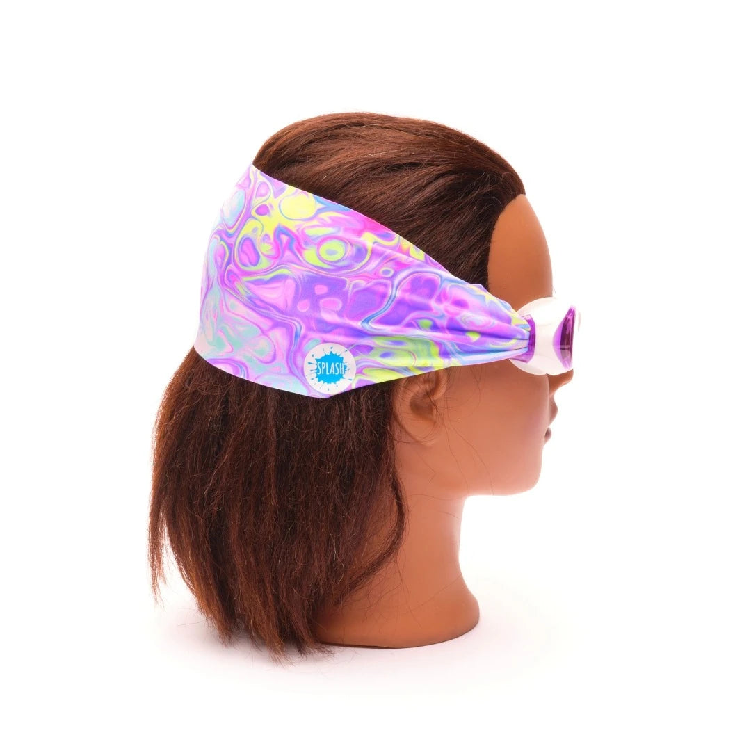 Child wearing Splash Place pastel swirl swim goggles with a no-tangle fabric strap and purple-tinted lenses.