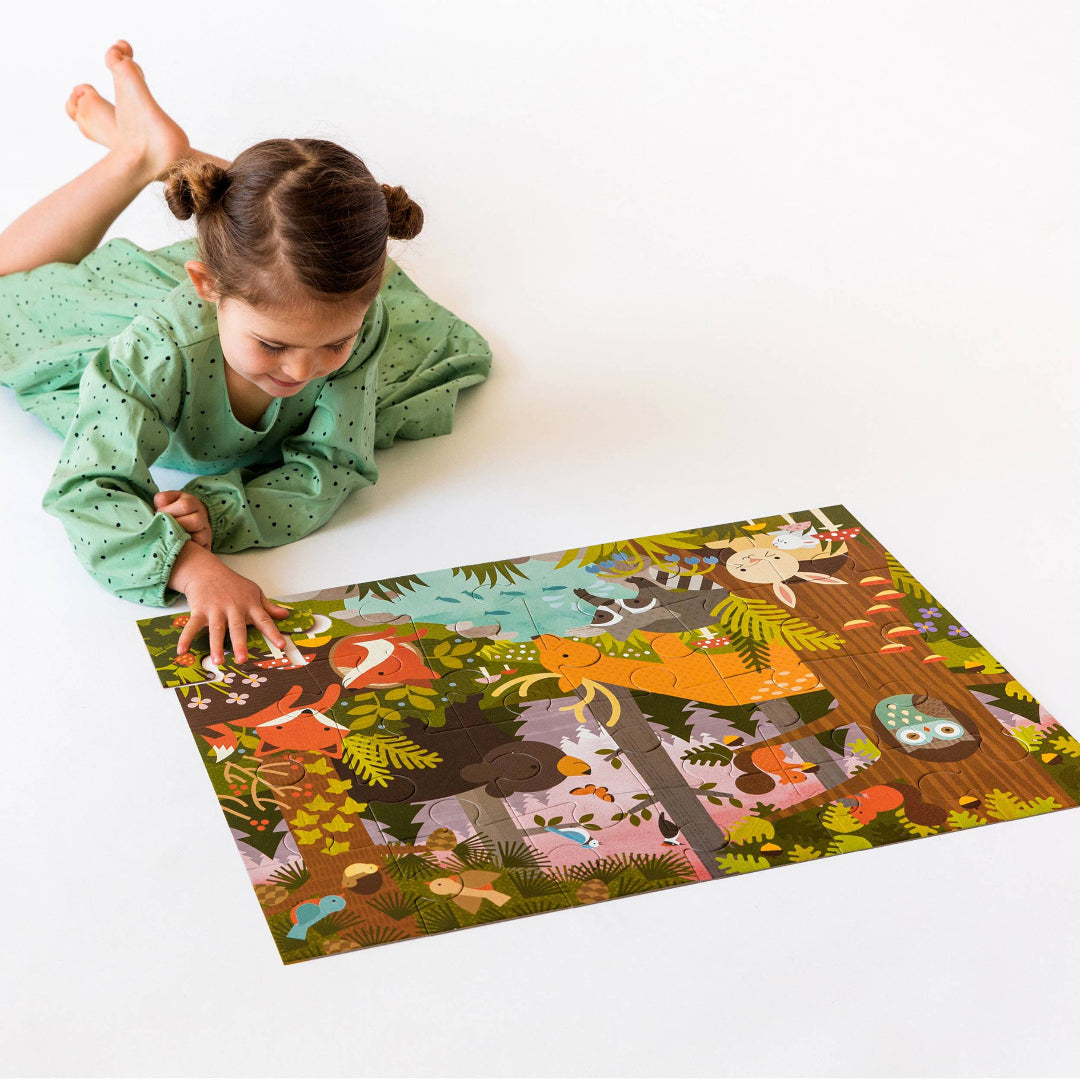 Child playing with a forest-themed puzzle on a white floor