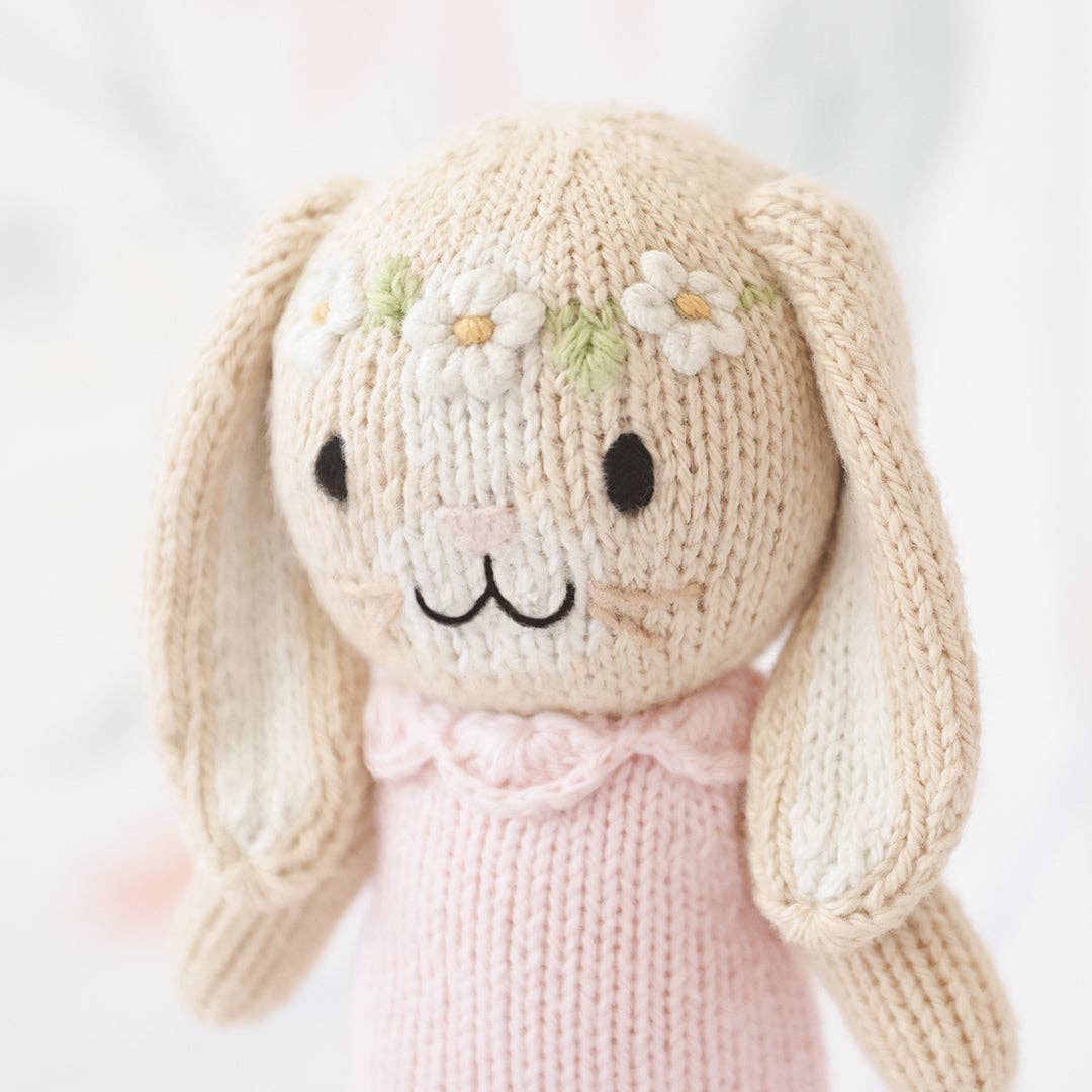 Knitted toy rabbit with a pink dress on a light background