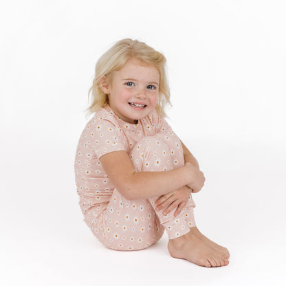 Young girl wearing a pink floral outfit on a white background