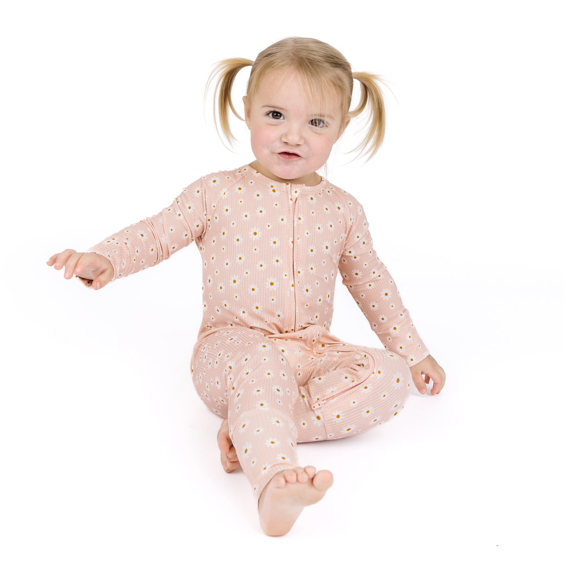 Child wearing a pink floral onesie on a white background