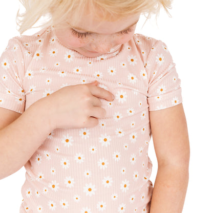 Child wearing a pink shirt with a floral pattern on a white background
