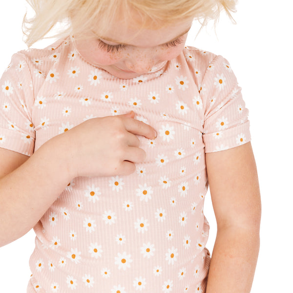 Child wearing a pink shirt with a floral pattern on a white background