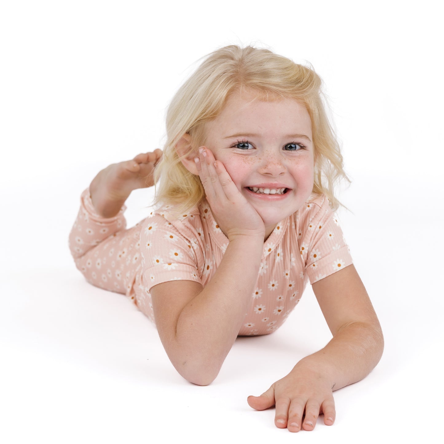Young girl lying on a white surface with a white background