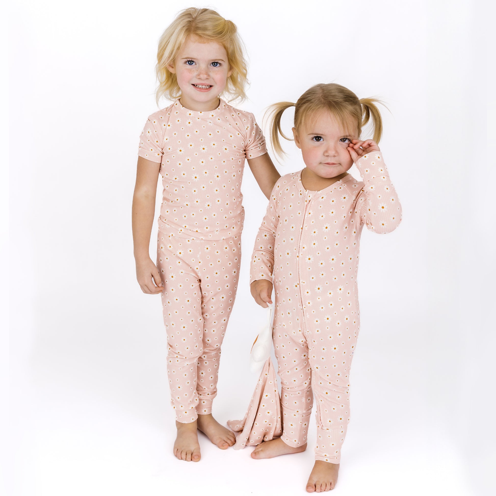 Two children wearing matching pink pajamas with a star pattern on a white background