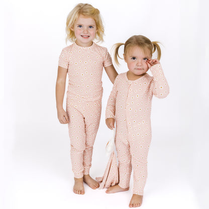 Two children wearing matching pink pajamas with a star pattern on a white background