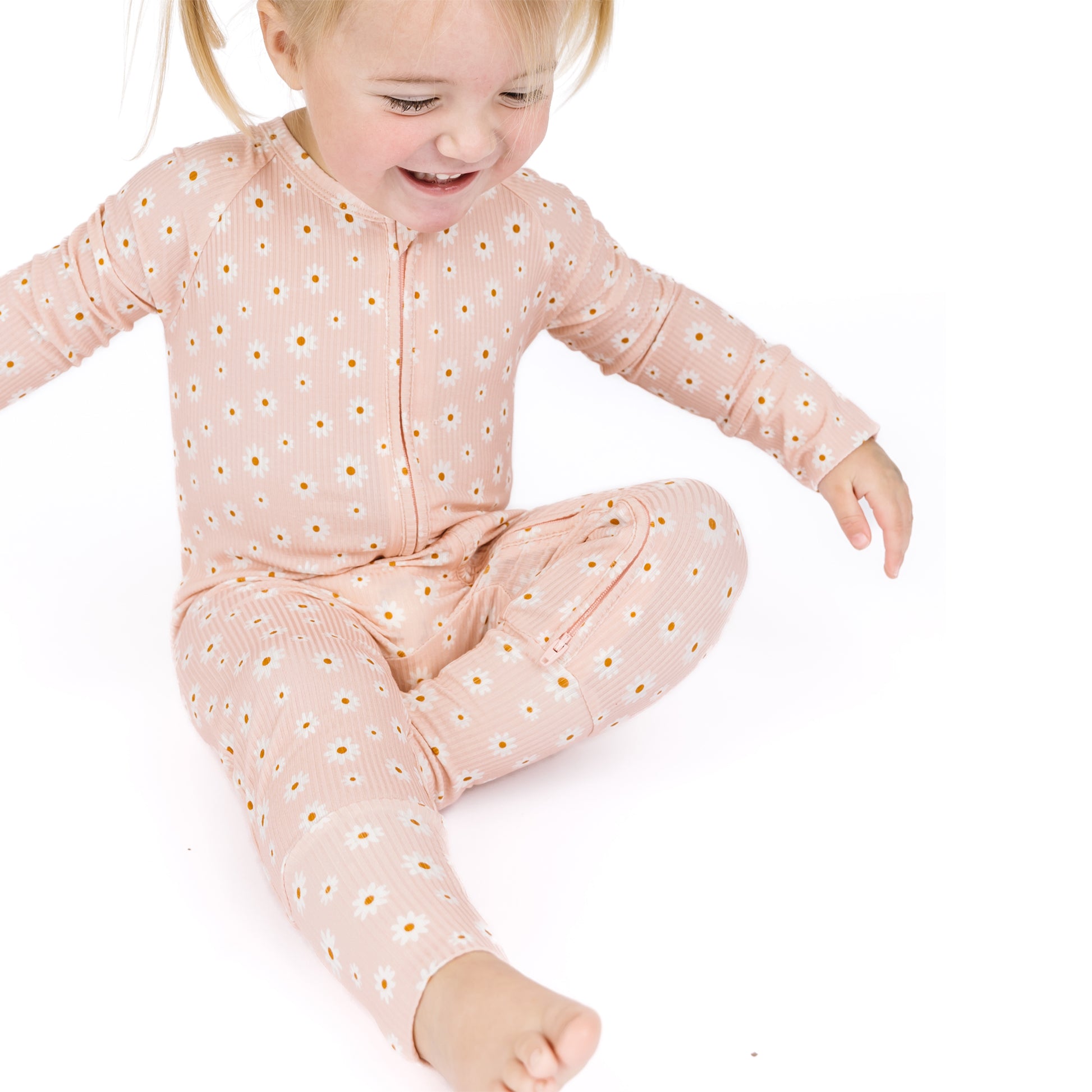 Child wearing a pink onesie with white polka dots on a white background