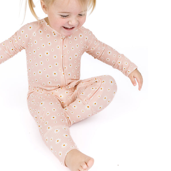 Child wearing a pink onesie with white polka dots on a white background