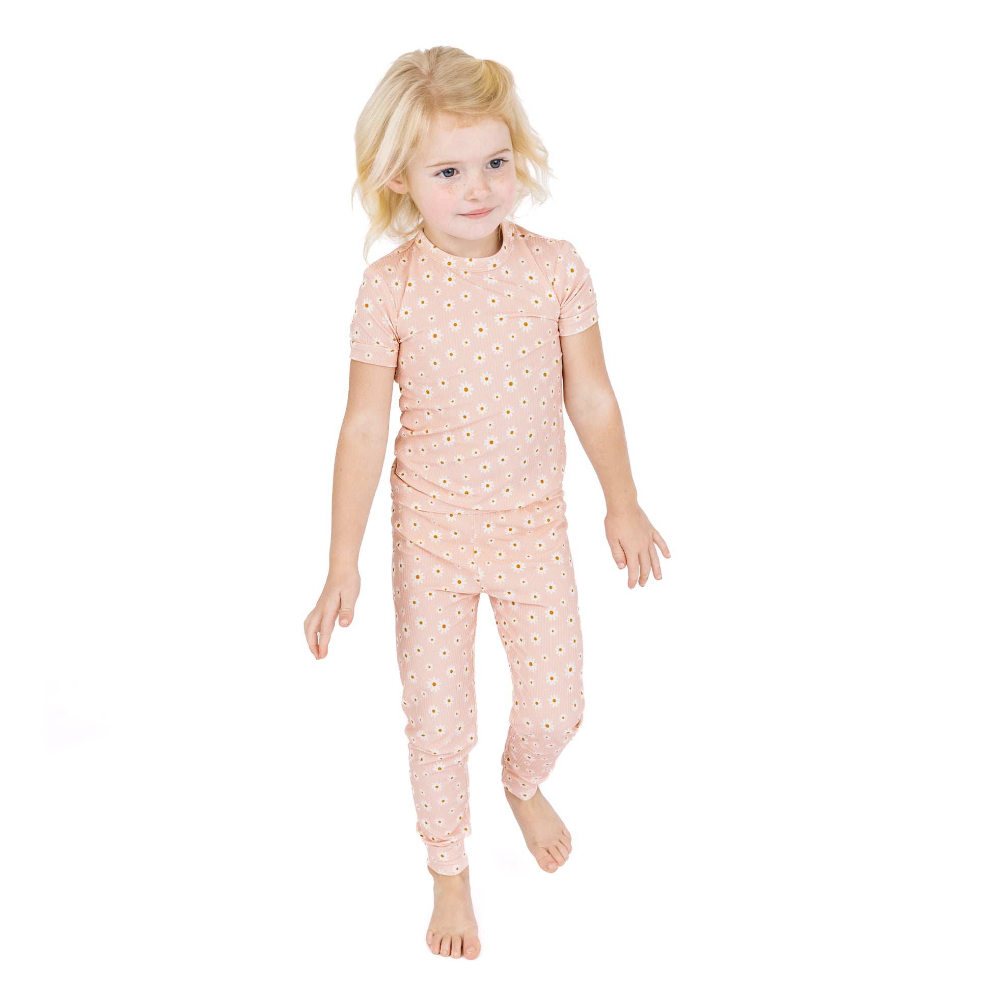 Child wearing a pink floral pajama set on a white background