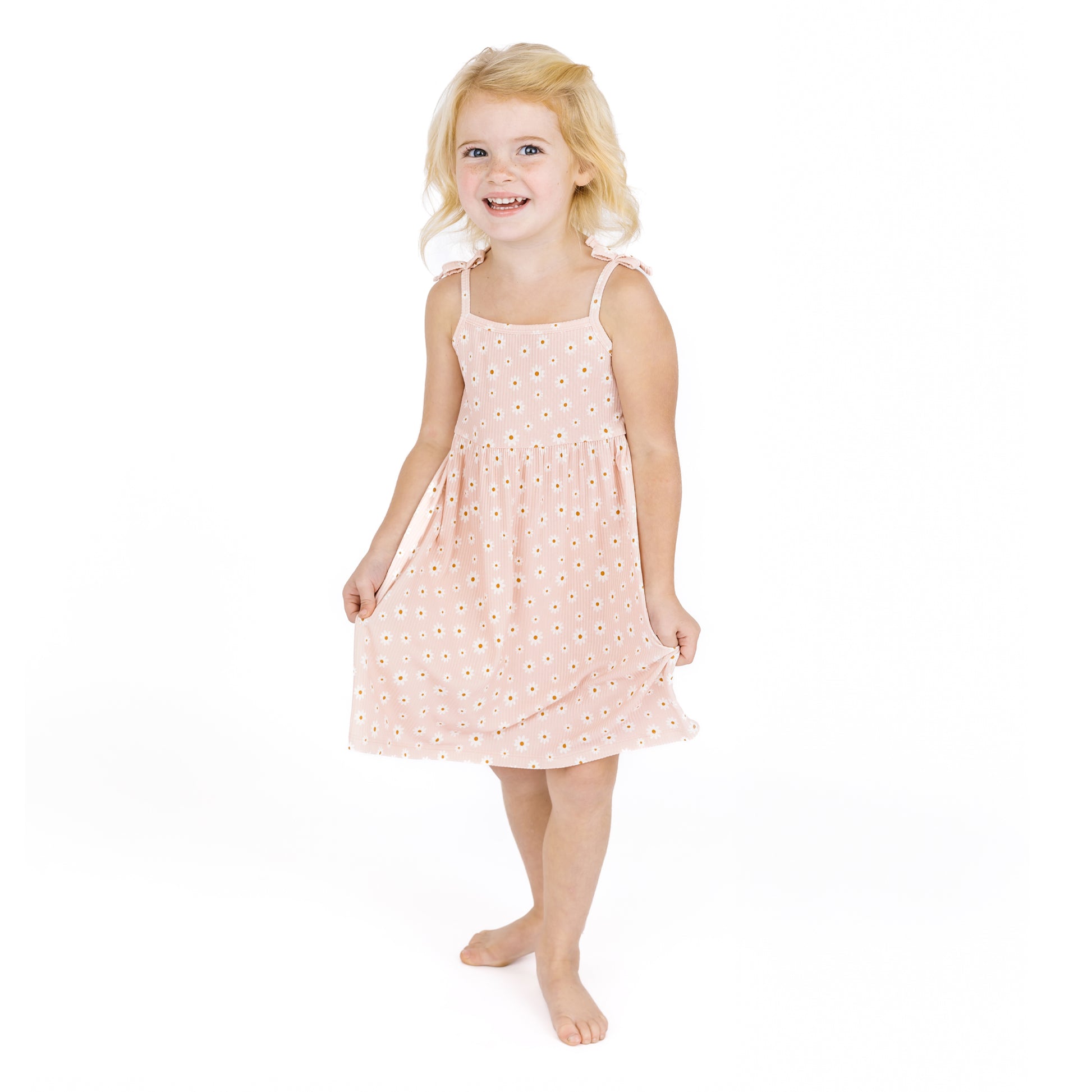 Young girl wearing a pink dress with white polka dots on a white background