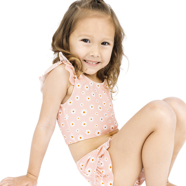 Young girl wearing a pink floral swimsuit on a white background