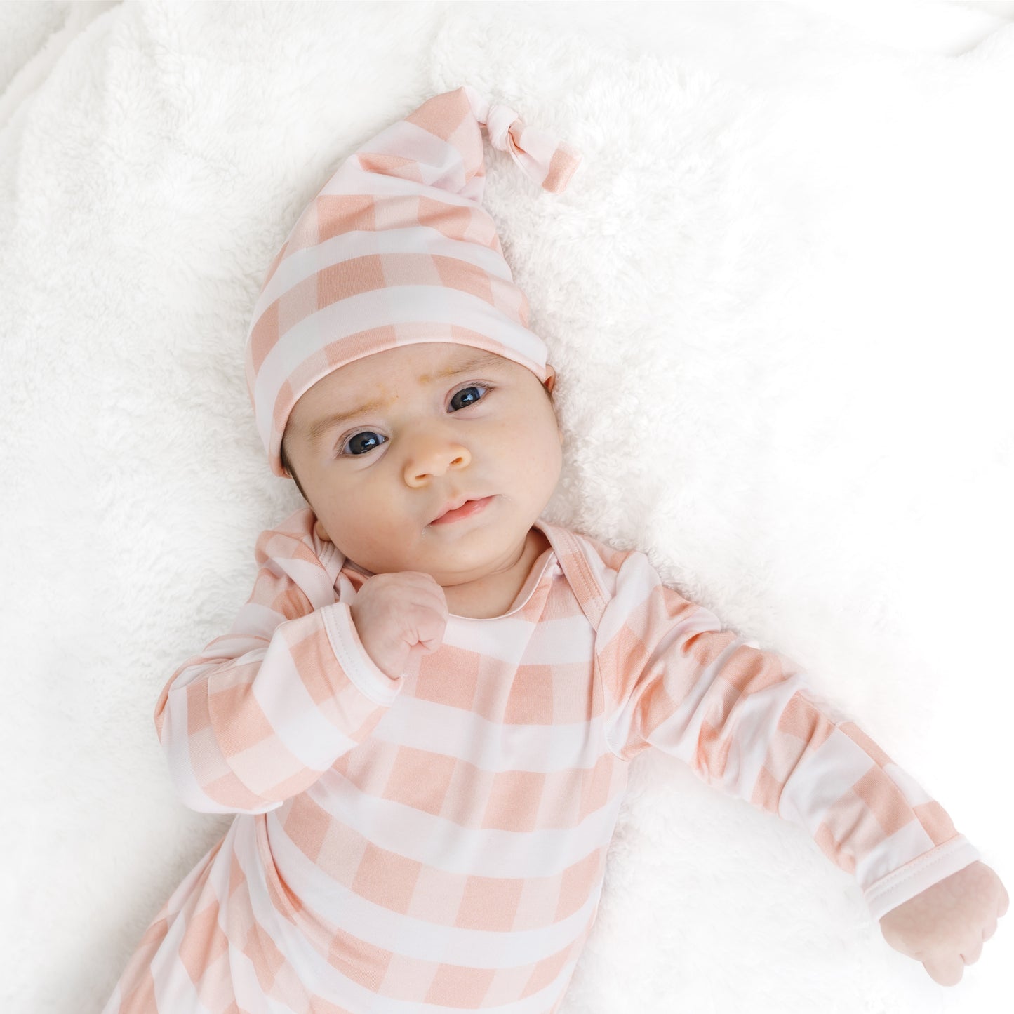 Sleeping newborn baby comfortably wrapped in the soft Pink Gingham bamboo tie-bottom gown and hat.