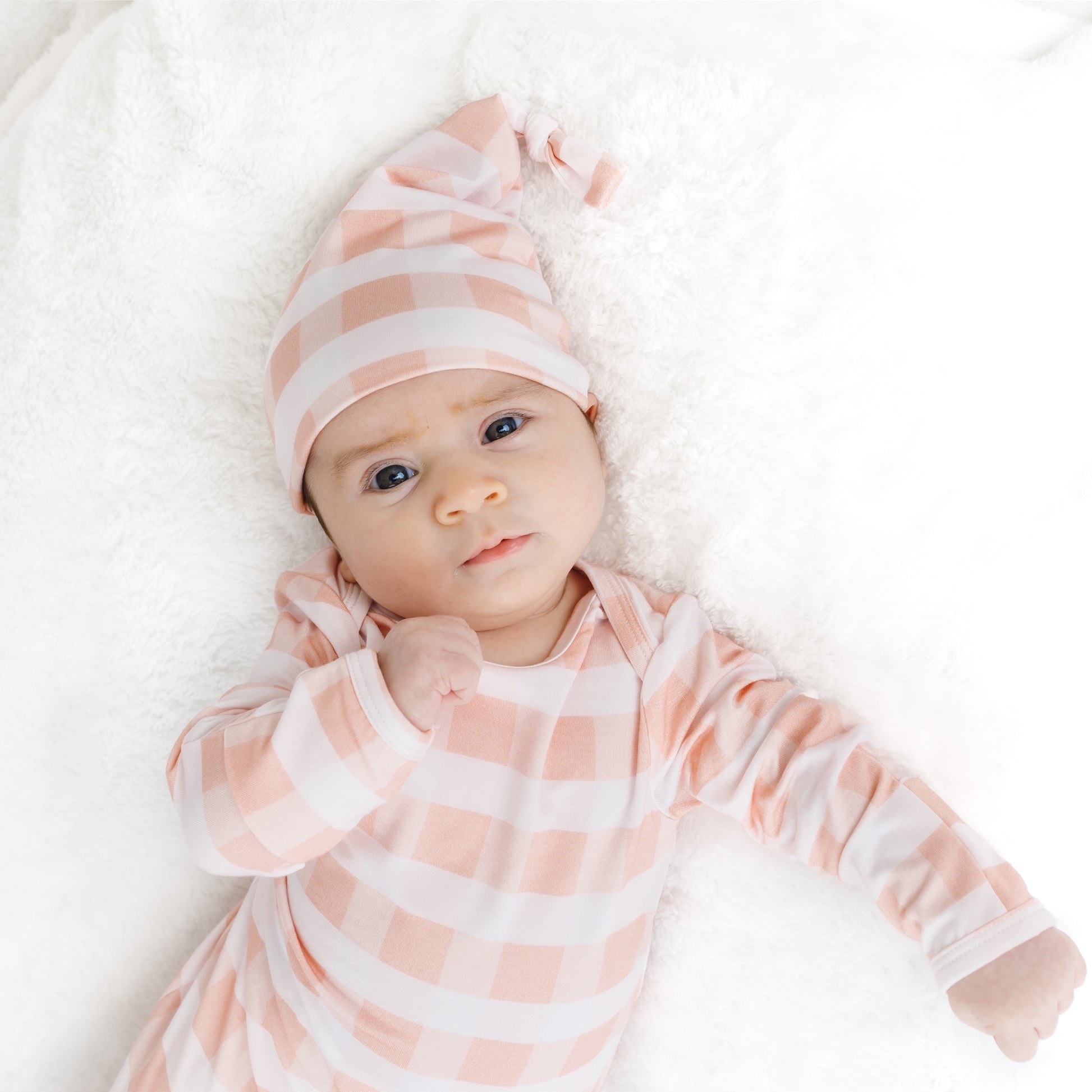 Sleeping newborn baby comfortably wrapped in the soft Pink Gingham bamboo tie-bottom gown and hat.