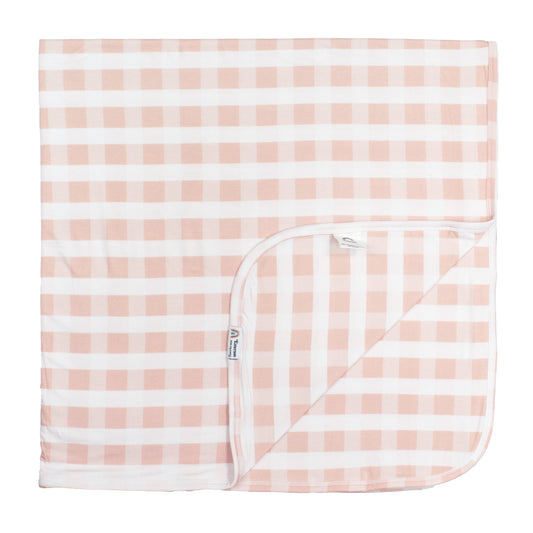 Pink and white checkered baby blanket with a corner folded over on a white background