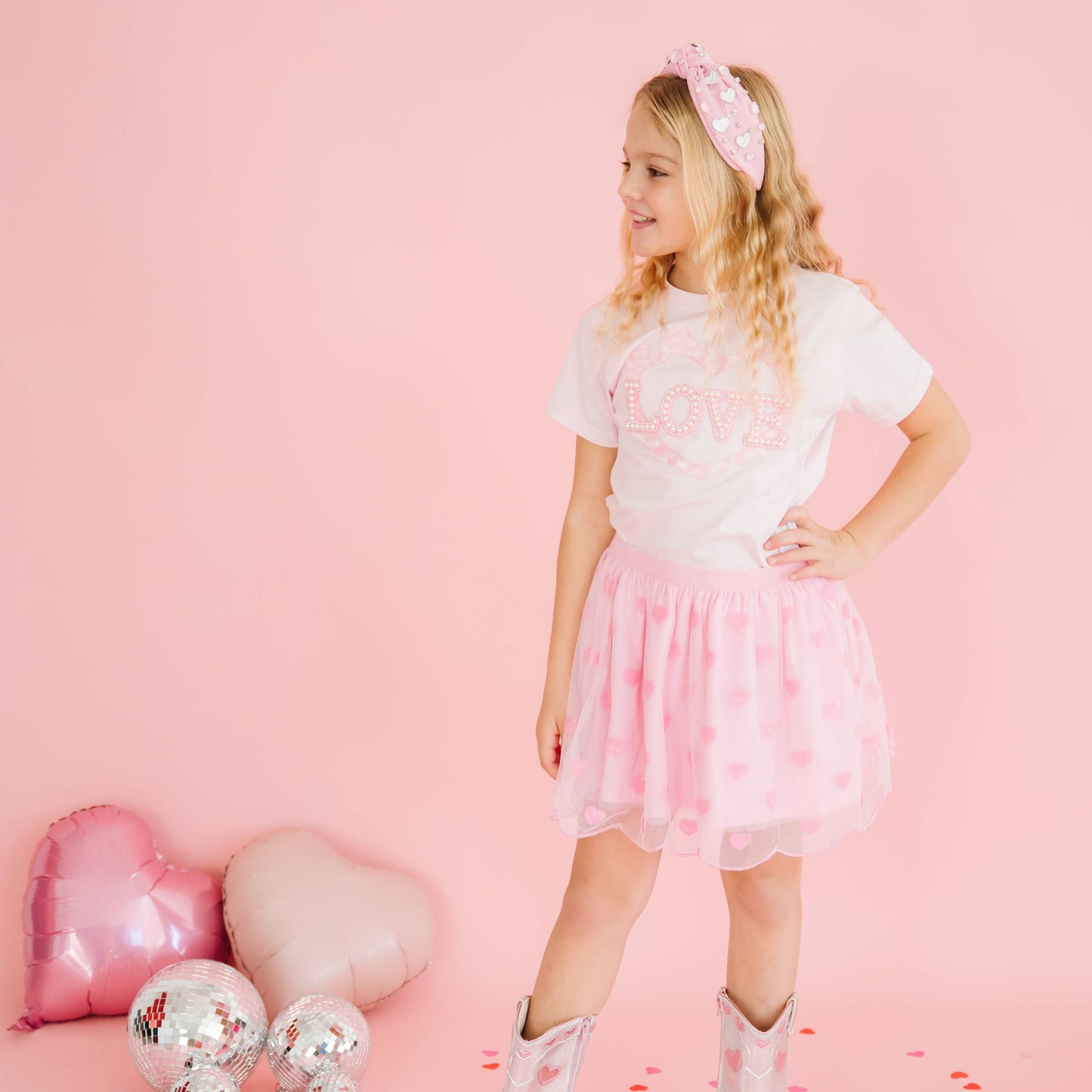 Side view of child wearing pink heart sequin tutu skirt.