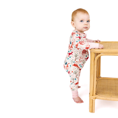 Baby standing while wearing bamboo zip pajama with dinosaur print.