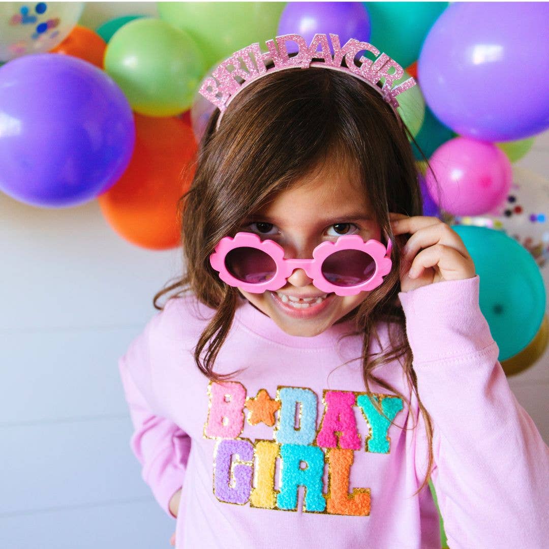 little girl wearing pink headband with glittery letters saying birthday girl on the top