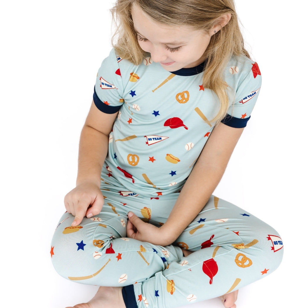 Child wearing a light blue pajama set with sports-themed print on a white background
