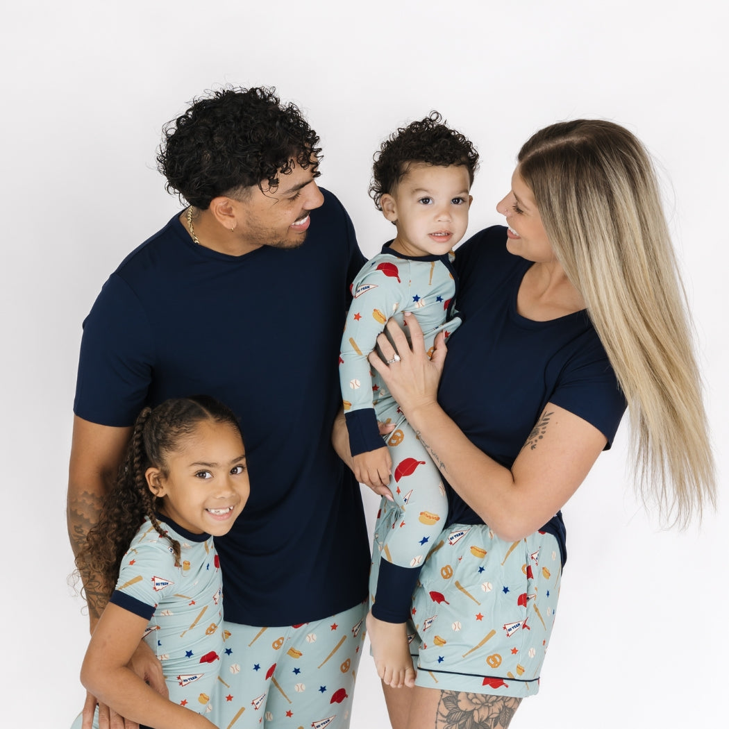 Family of four wearing matching pajamas against a white background