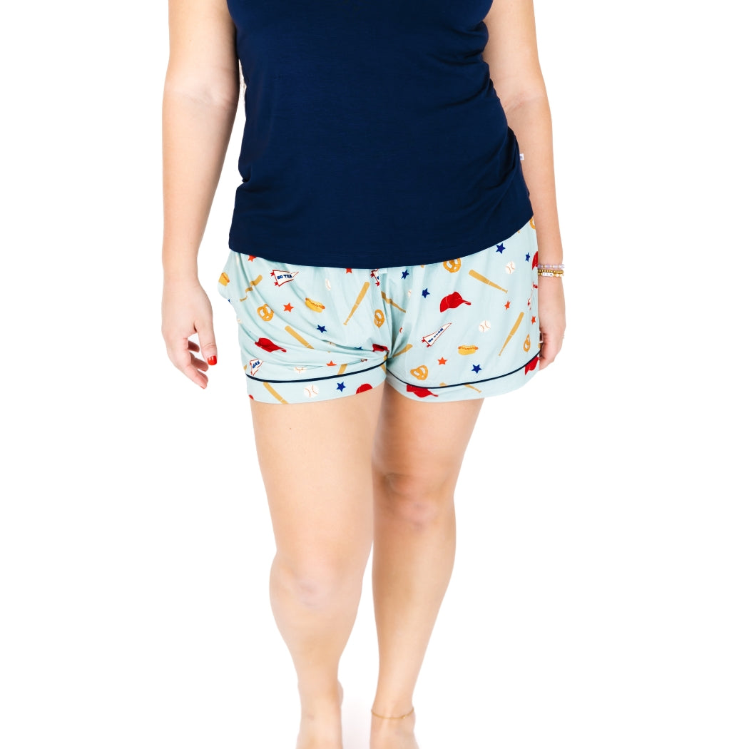 Person wearing a navy top and patterned shorts on a white background