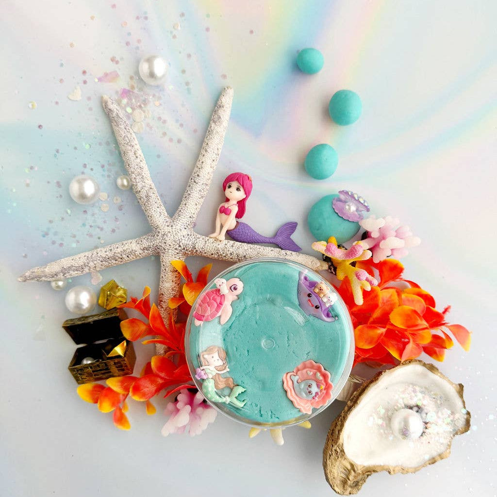 Decorative item with mermaid figurine, starfish, and colorful elements on a pastel background