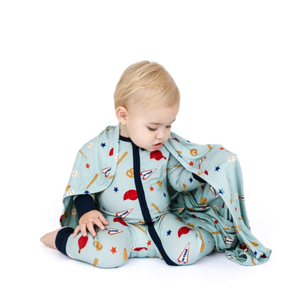Child sitting on a white background with a patterned blanket and outfit.