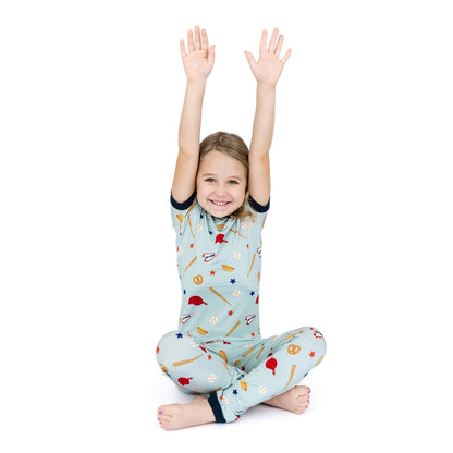 Child wearing a colorful pajama set with raised arms on a white background