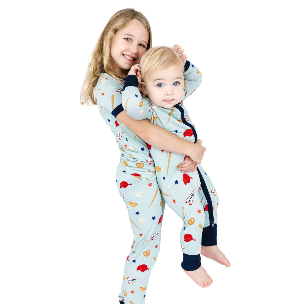 Two children wearing matching pajamas with space-themed designs on a white background