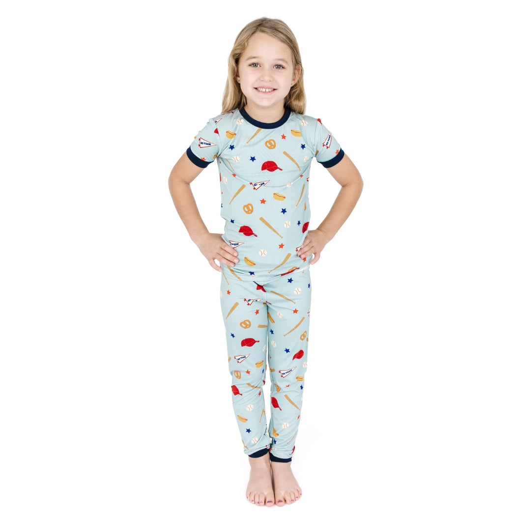 Child wearing a light blue pajama set with sports-themed design on a white background