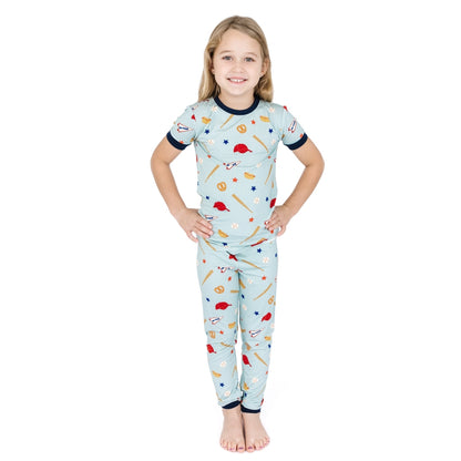 Child wearing a light blue pajama set with sports-themed design on a white background