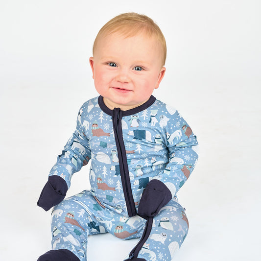 Baby sitting in white background with blue polar bear pajamas 