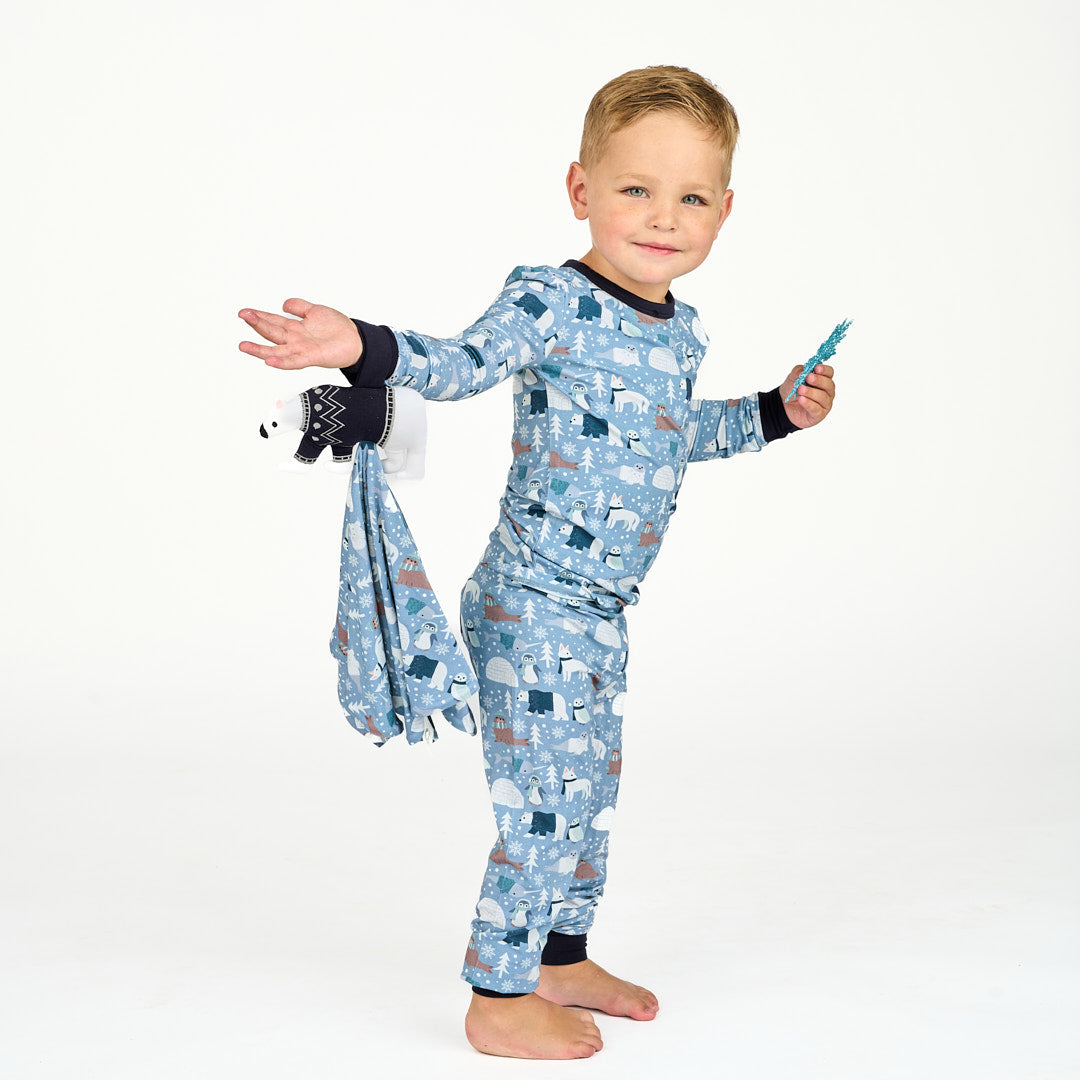 Toddler standing in white background with polar pals pajama two-piece featuring polar bears and holding the lovey