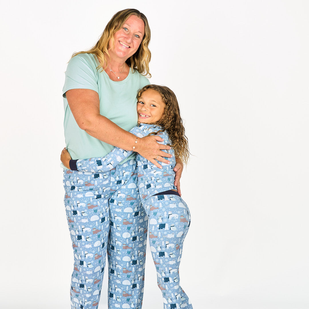 Mother and daughter hugging standing in white background with polar pals pajamas featuring polar bears