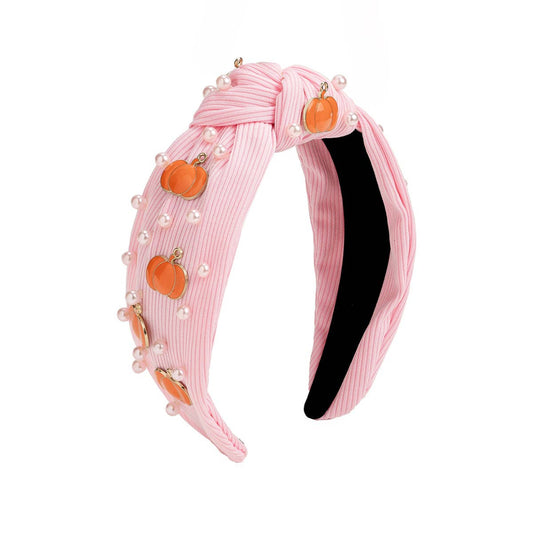 pink headband with white pearls and orange pumpkin charms attached